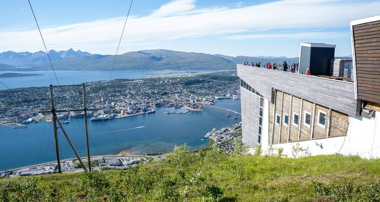Plateforme d'observation au sommet d'une colline surplombant la ville de Tromsø, les fjords et les montagnes par une journée ensoleillée.