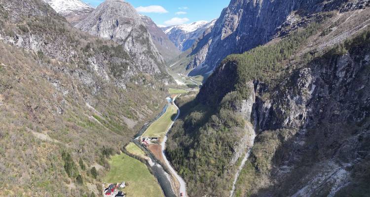 Vue aérienne élevée d'une vallée étroite et verdoyante avec une rivière sinueuse, des fermes dispersées et des falaises rocheuses escarpées de part et d'autre.