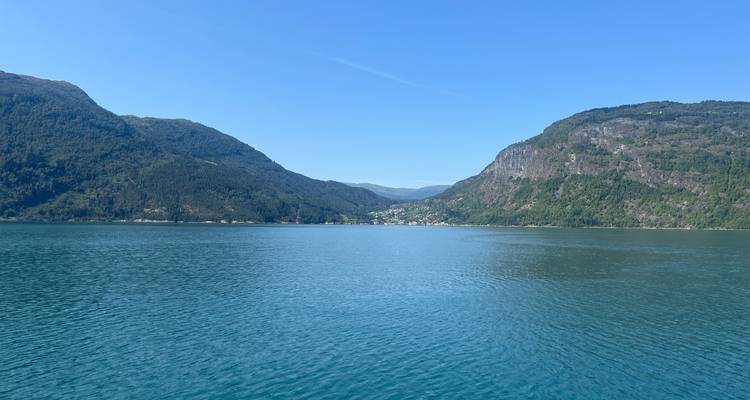 Calme fjord bleu encadré par des montagnes vertes sous un ciel d'été dégagé.