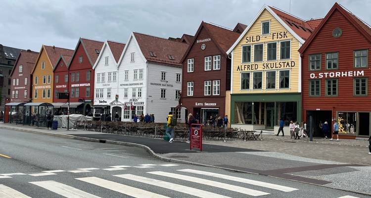 Rangée de maisons colorées en bois de Bryggen avec des cafés en plein air et des piétons le long d'une rue de Bergen.