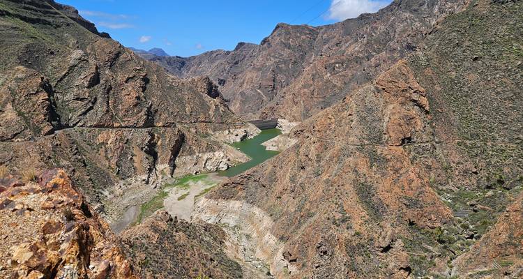 Canyon sauvage et escarpé avec un réservoir étroit aux eaux verdâtres et des parois rocheuses arides s'étendant au loin.