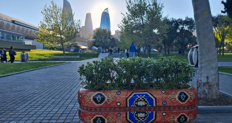 Chemin du parc urbain avec jardinière à motif de tapis décoratif et les Tours de la Flamme rétroéclairées par un soleil bas