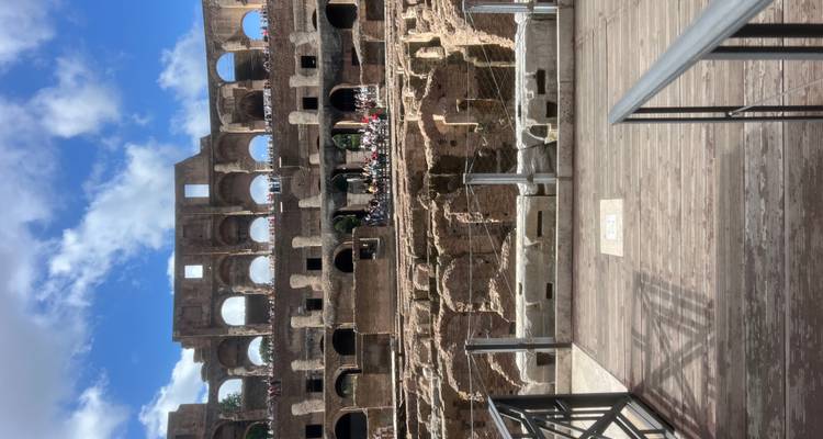 Filas de arcos antiguos dentro del Coliseo con visitantes observando desde pasarelas de madera.