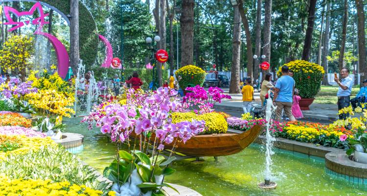 Parque colorido de la ciudad con exhibiciones de orquídeas, fuentes y visitantes disfrutando de un festival de flores.