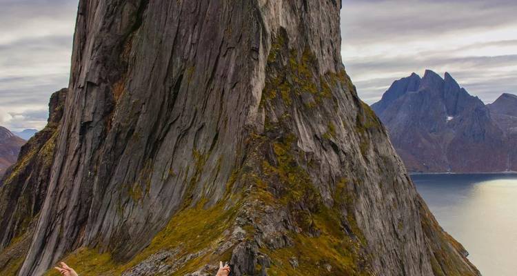 Les randonneurs aventureux progressent prudemment le long d'une crête étroite à côté d'une paroi rocheuse à pic surplombant un fjord.