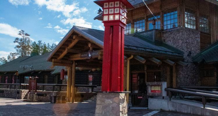 Log building complex with a distinctive red lantern-style column on a sunny day