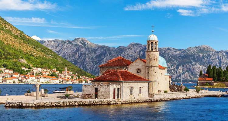 Eilandkerk Onze-Lieve-Vrouw van de Rotsen tegen dramatische bergen en de blauwe baai van Kotor.