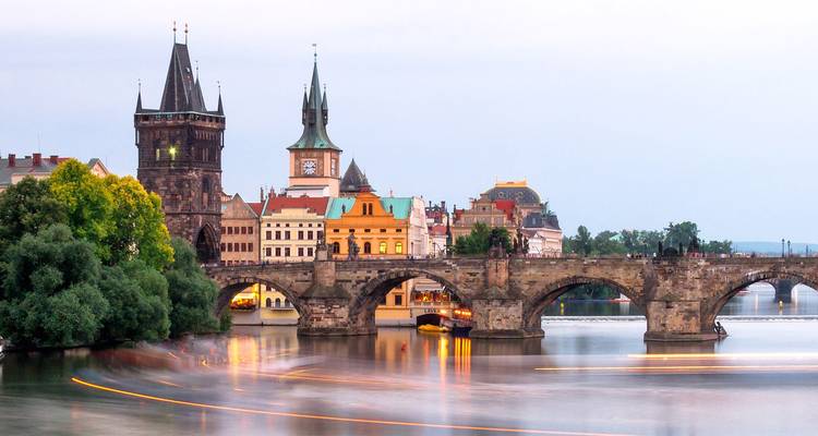 Abendaufnahme mit langer Belichtungszeit der Karlsbrücke mit unscharfen Bootslichtern auf der Moldau