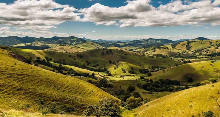 Rolling green hills and valleys under scattered clouds in Queensland’s hinterland.