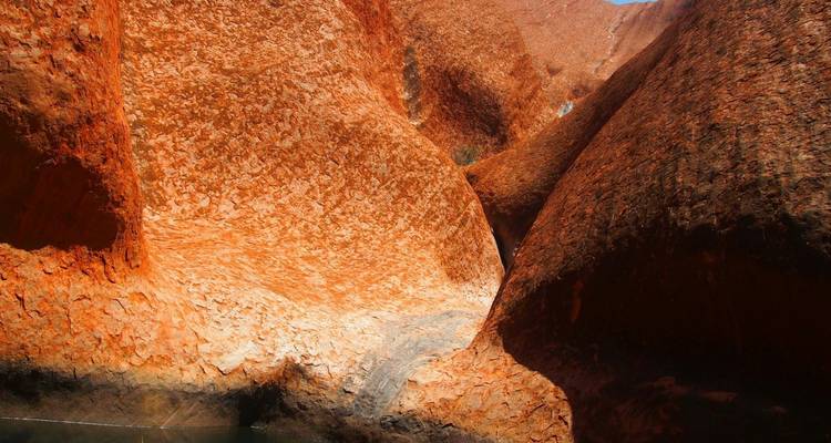 Nahaufnahme von tiefroter Sandsteinwänden und Spalten im Red Centre von Australien unter hellem Licht.