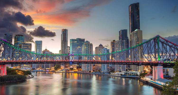Kleurrijke lichten verlichten de Story Bridge met de skyline van Brisbane met hoge gebouwen in de schemering.