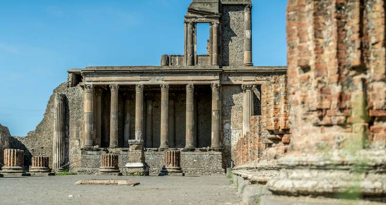 Oude tempel met zuilen in puin in Pompeii tegen een heldere blauwe lucht.