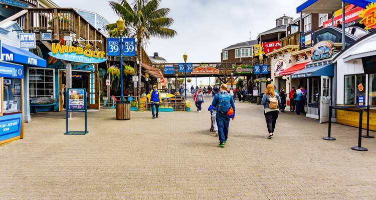 Les visiteurs se promenant le long des boutiques et des restaurants du Pier 39 par un jour nuageux.