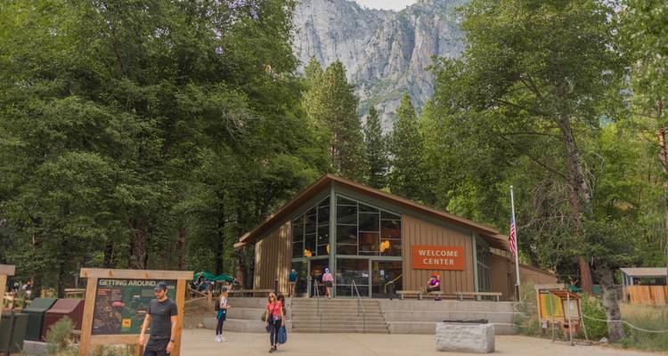 Le Centre d'accueil de Yosemite niché parmi de grands arbres avec des falaises de granit s'élevant derrière.