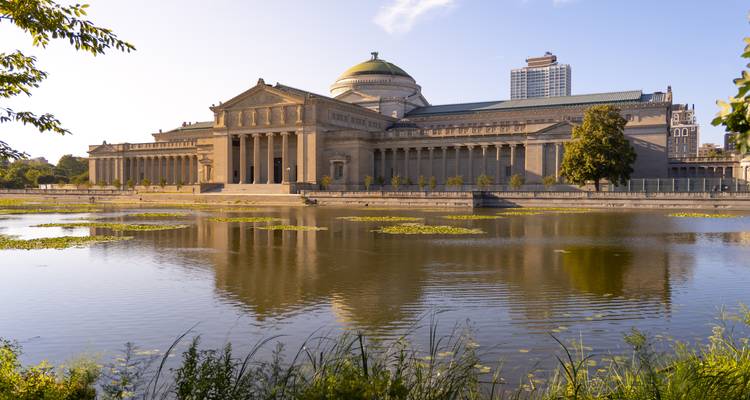 Élégant Musée de la Science et de l'Industrie se reflétant dans un lagon tranquille avec un ciel bleu.