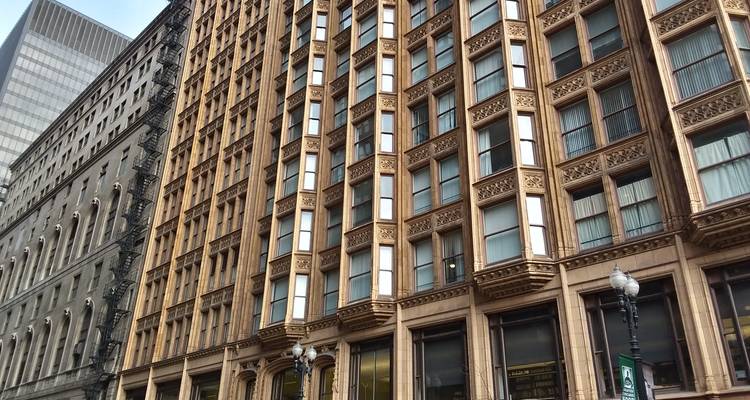 Façade détaillée d'un bâtiment historique de Chicago avec des encadrements de fenêtres ornementés à la lumière chaude.