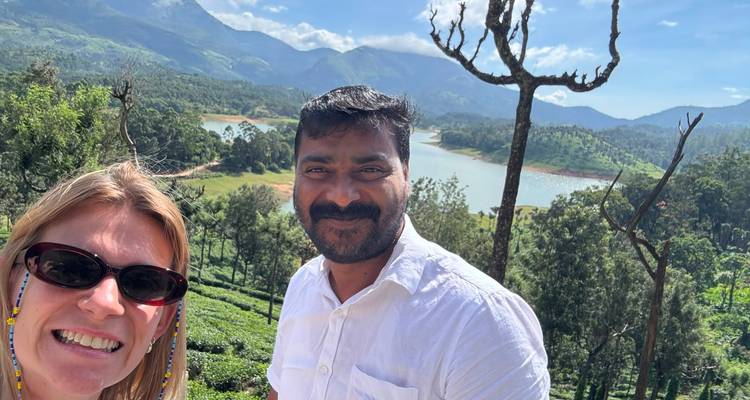 Lächelnde Reisende mit Bergsee, Wald und Gipfeln hinter ihnen in den Highlands von Kerala.