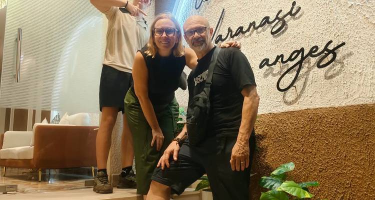 Innenaufnahme von drei Reisenden, die an einem dekorativen Wandschild in einer Cafè-Lobby posieren.