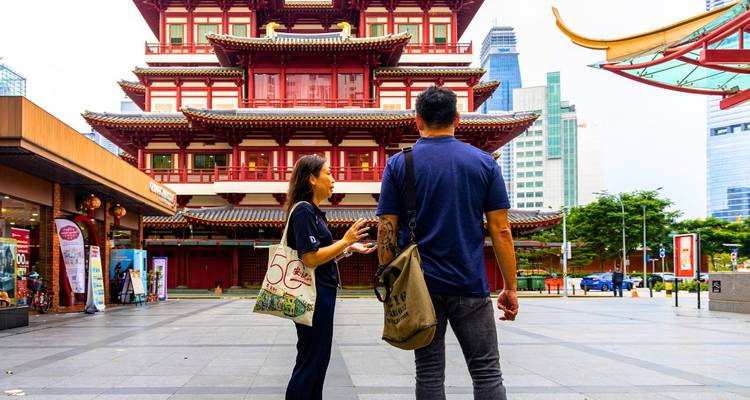 Reiseleiter und Besucher unterhalten sich vor dem prunkvollen Buddha Tooth Relic Temple im Chinatown von Singapur.