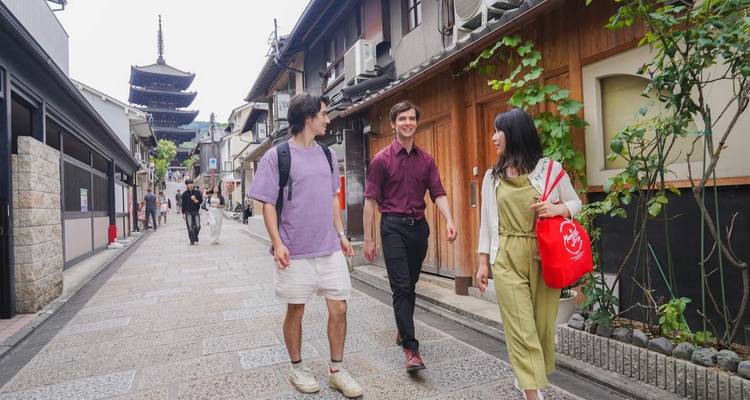 Drei Freunde schlendern die historische Yasaka-Pagoden-Gasse in Kyoto entlang, die von traditionellen Holzhäusern gesäumt ist.