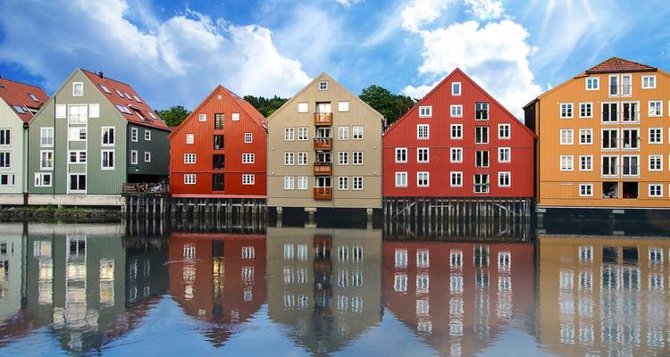 Almacenes coloridos de madera en el frente del río en Trondheim reflejados perfectamente en el río en un día soleado