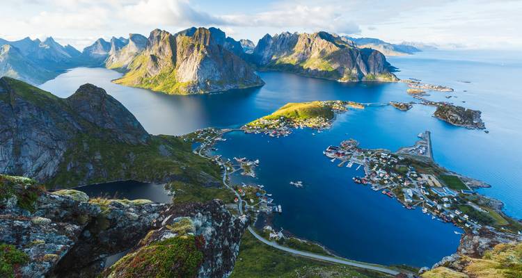 Toma aérea panorámica del archipiélago de Lofoten con picos escarpados y un mar azul cobalto bajo una luz suave