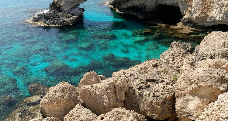 Laguna costera turquesa con arco de roca y acantilados de piedra caliza sobre aguas cristalinas del Mediterráneo