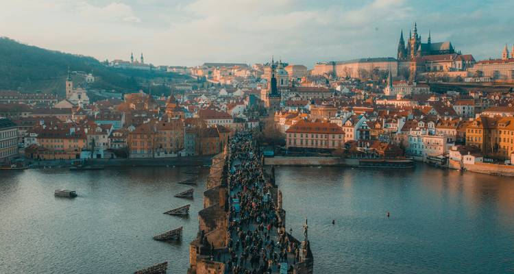 Fotografía aérea diurna del Puente de Carlos lleno de peatones atravesando el río Vltava hacia el Castillo de Praga