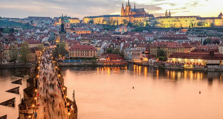 Vista del atardecer del Castillo de Praga iluminado y el Puente de Carlos reflejándose en el Vltava al anochecer