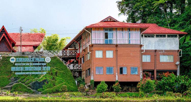 Les bâtiments du centre des visiteurs du parc Kinabalu nichés au milieu d'une verdure luxuriante avec un panneau de site du patrimoine mondial.