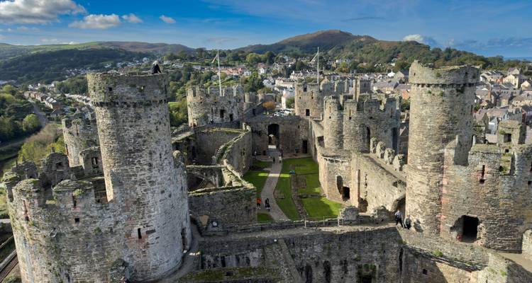 Vista de dron dentro de las murallas fortificadas y torres del Castillo de Conwy con visitantes explorando las ruinas.