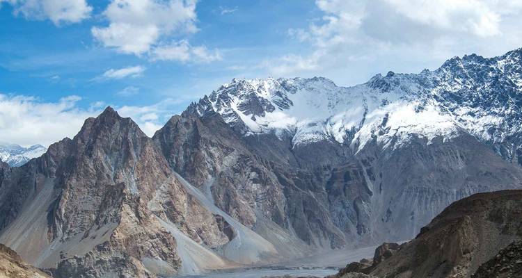 Les pics dentelés couverts de neige du Karakoram s'élèvent majestueusement au-dessus des vallées rocheuses sous des ciels bleus.