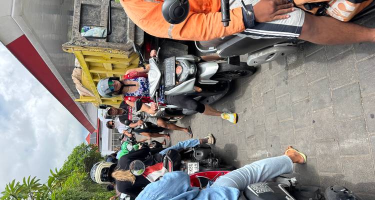 Calle angosta y congestionada llena de gente en motos y scooters esperando en el tráfico.
