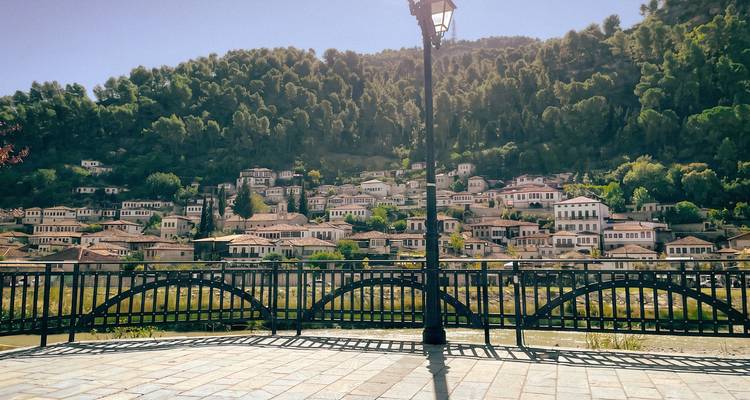 Vista panorámica de las casas en la ladera de Berat al otro lado del río, enmarcada por una farola.