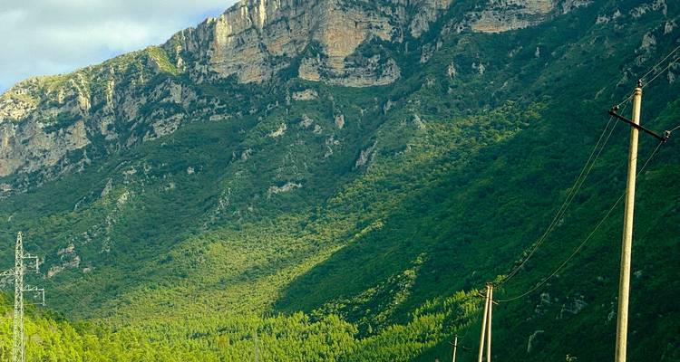 Les pentes montagneuses couvertes de forêt avec des lignes électriques traversant la vallée.