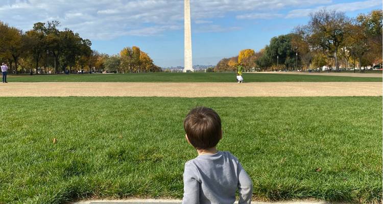 Un enfant se tient sur le National Mall en regardant vers le lointain Monument de Washington