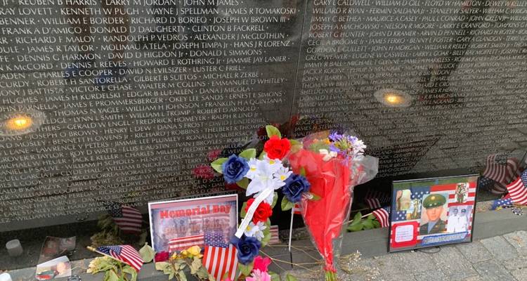 Des fleurs et des souvenirs placés contre le mur poli en granit noir du Mémorial des anciens combattants du Viêt Nam
