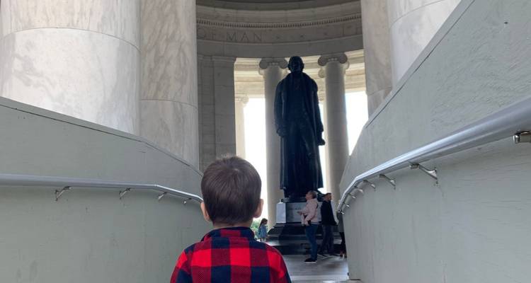Un petit enfant à l'intérieur du Jefferson Memorial regarde vers le haut la statue en bronze de Thomas Jefferson.