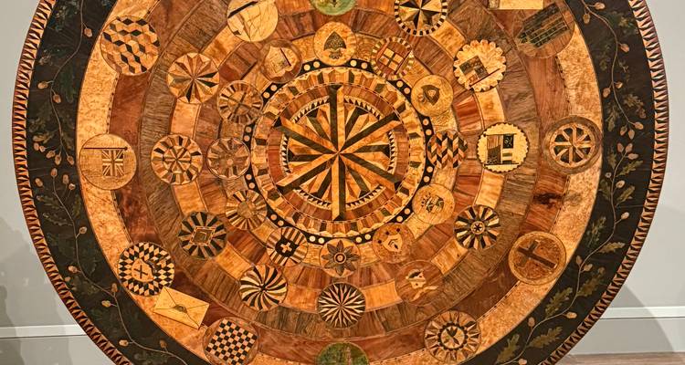 Plateau de table en marqueterie de bois détaillé présentant des cercles concentriques de symboles incrustes complexes.