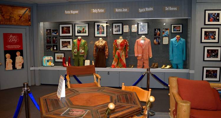 Ausstellung von farbenfrohen Bühnenkostümen und Fotos von Country-Music-Legenden in einer Museumsvitrine.