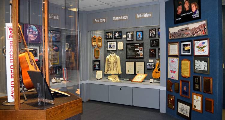 Raum mit Country-Musik-Memorabilien, in dem Gitarren, Goldschallplatten und Fotos hinter Glas ausgestellt sind.