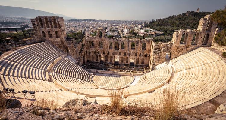 Stone seating and stage of the Odeon of Herodes Atticus with Athens city in background on a sunny day