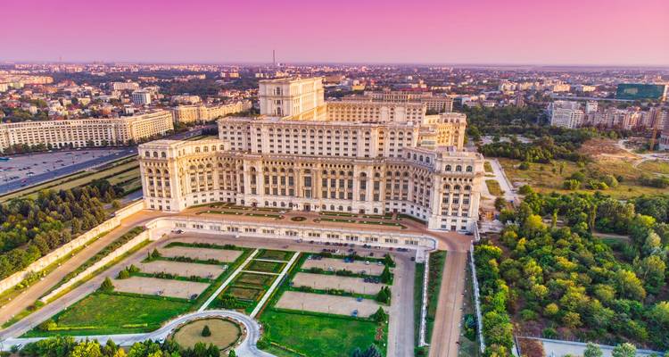 Zonsopgang gloed op het kolossale Paleis van het Parlement met uitzicht op formele tuinen in Boekarest
