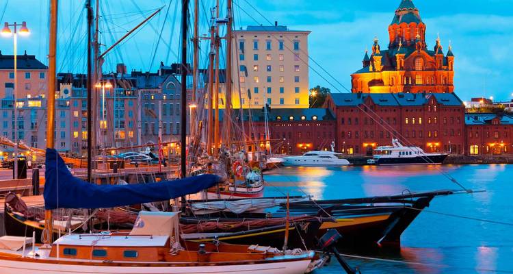 Avondhaven scene in Helsinki met zeilboten en de verlichte Uspenski Kathedraal.