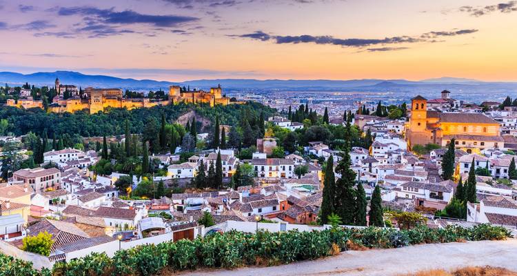 Vista panorámica al atardecer sobre Granada con el complejo de la Alhambra iluminado sobre la ciudad blanca