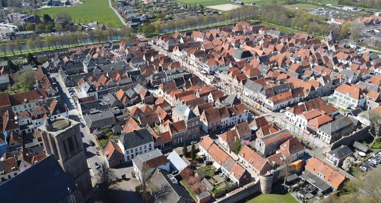 Drohnenaufnahme einer dicht bebauten europäischen Stadt mit Ziegeldächern und engen Straßen, die ein Flickwerksmuster bilden.