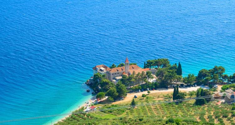 Luftaufnahme eines abgelegenen Küstenklosters, das von türkisblauem Wasser vor der Insel Brač umgeben ist.