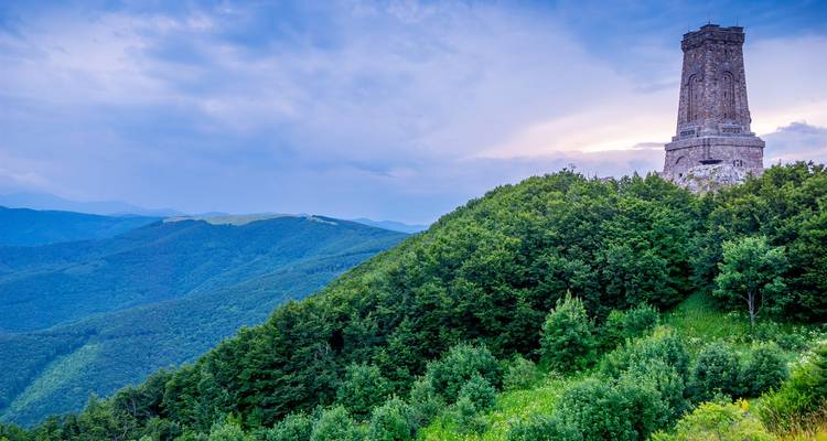 Der Denkmalturm Stone Shipka steht auf einem bewaldeten Bergrücken mit Blick auf die ausgedehnte Berglandschaft des Balkans.
