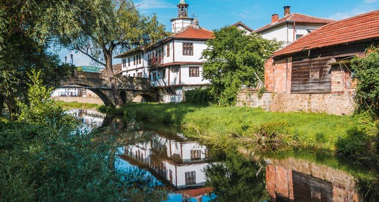Ruhige Flusslandschaft mit traditionellen bulgarischen Häusern, die sich im Wasser von Tryavna spiegeln.