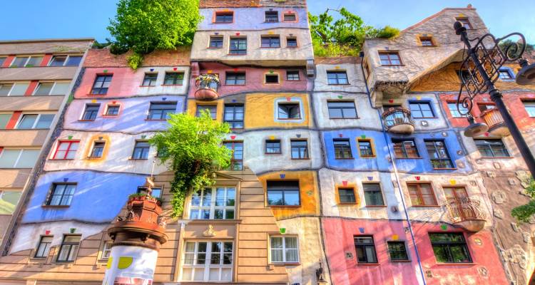 Farbenfrohe, verspielte Fassade des Hundertwasserhauses mit Bäumen bedeckt und unregelmäßigen Fenstern